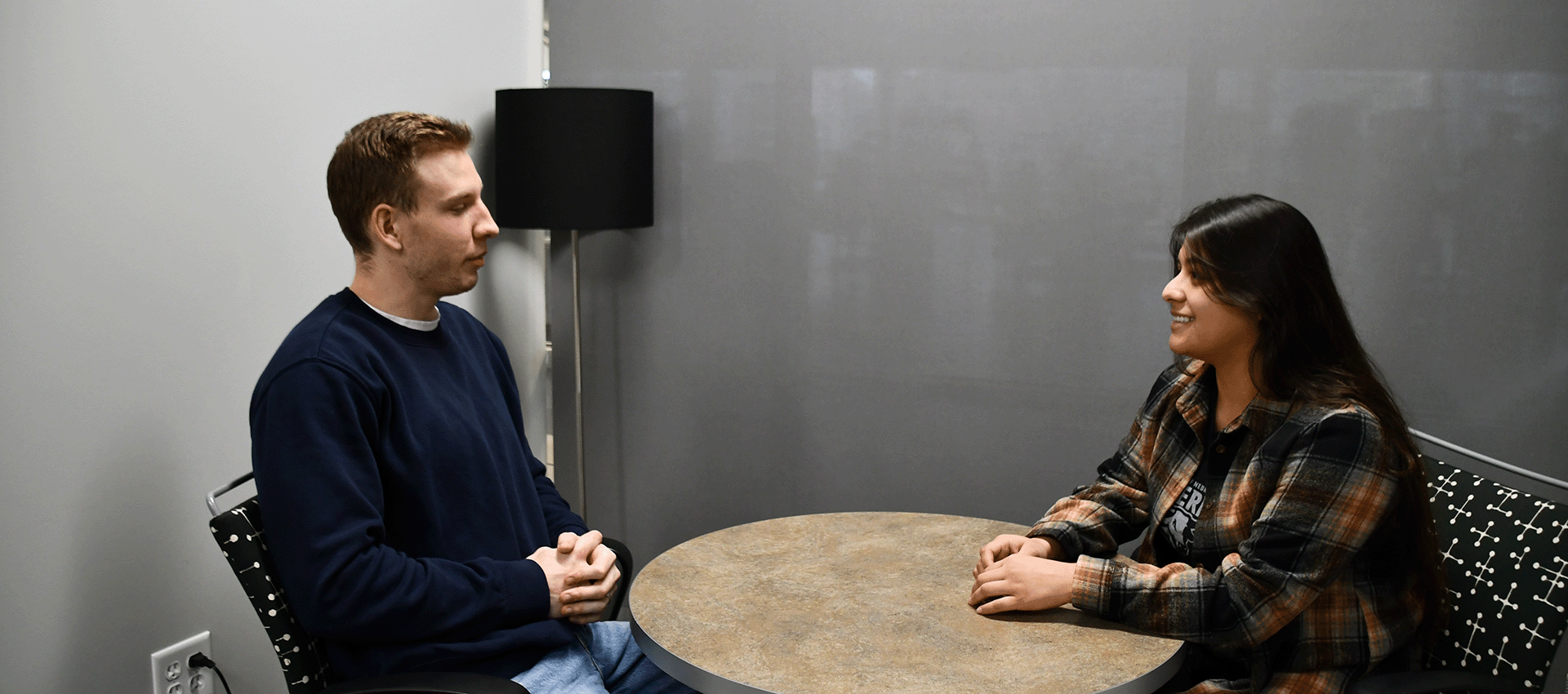 two people sit across from each other at a table.