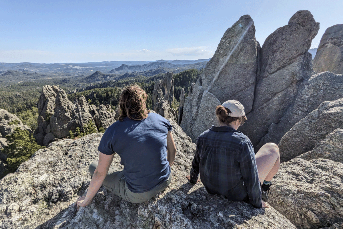 two people resting on top of a mountain.