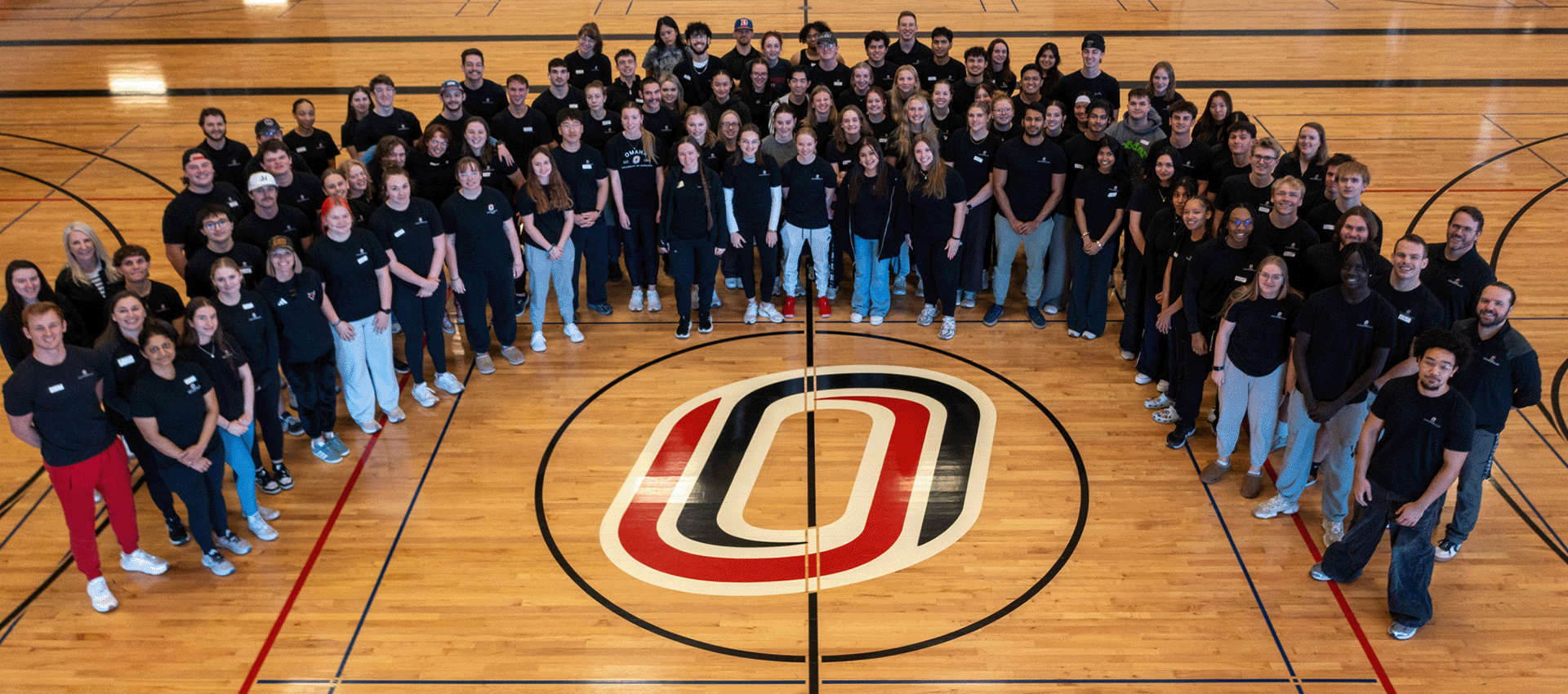 a group of people standing on a basketball court with UNO's O icon.