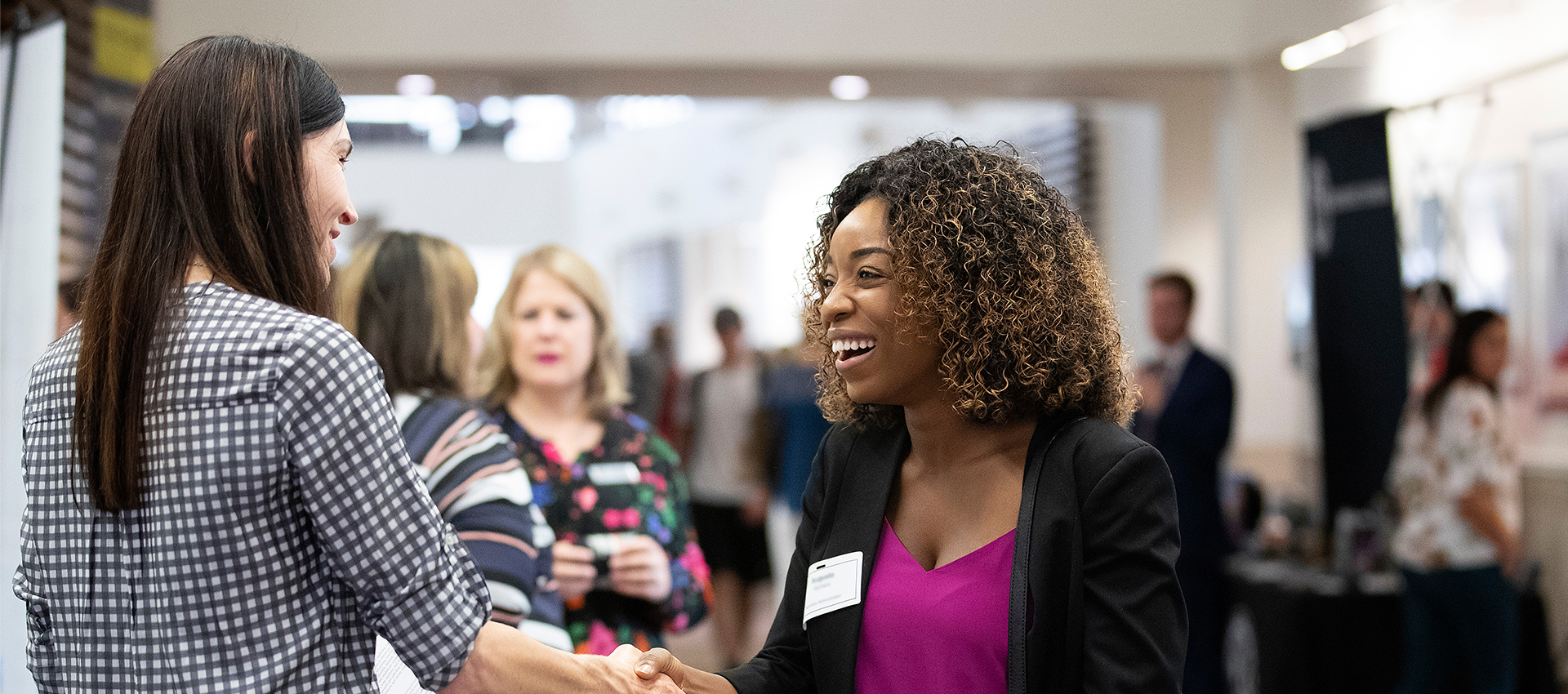 two women shaking hands and smiling