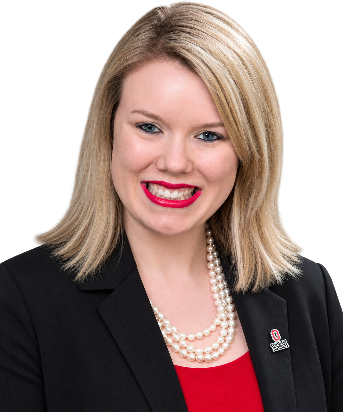 Portrait of a person with shoulder-length blonde hair, wearing a black blazer over a red top, a layered pearl necklace, and a lapel pin, smiling at the camera against a transparent background.