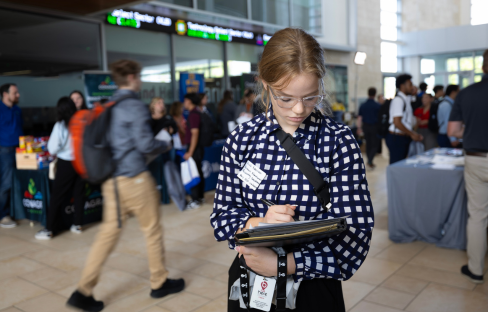 A student looking down at their notebook during a career fair.