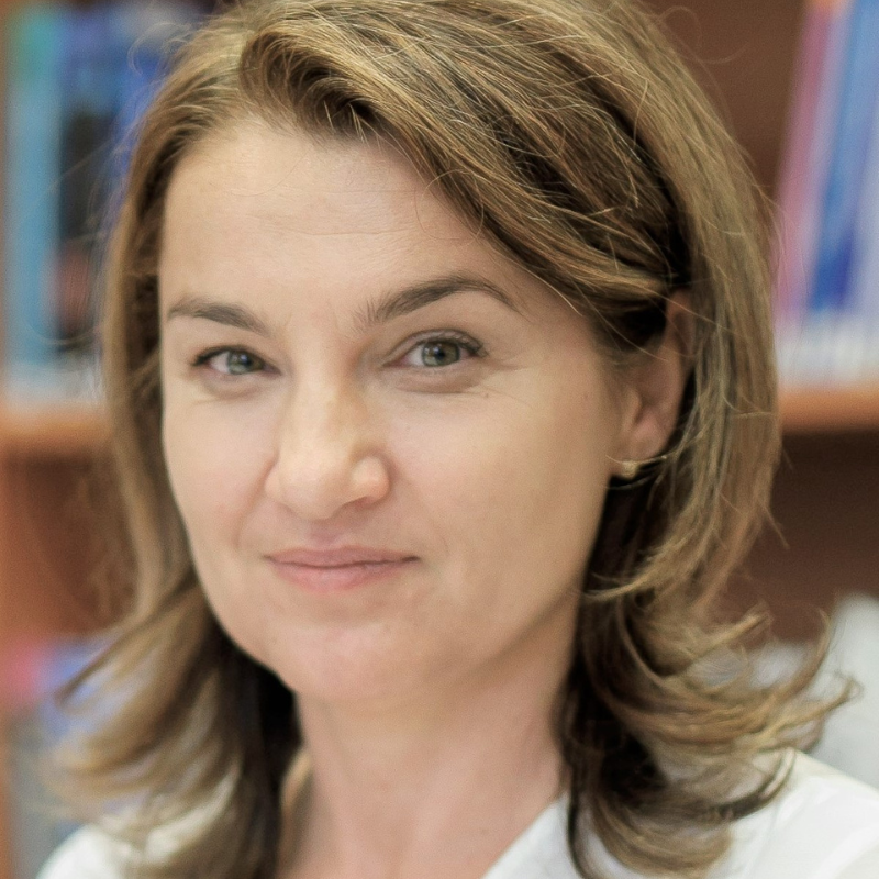 Lívia Körtvélyessy stands in front of a bookshelf.