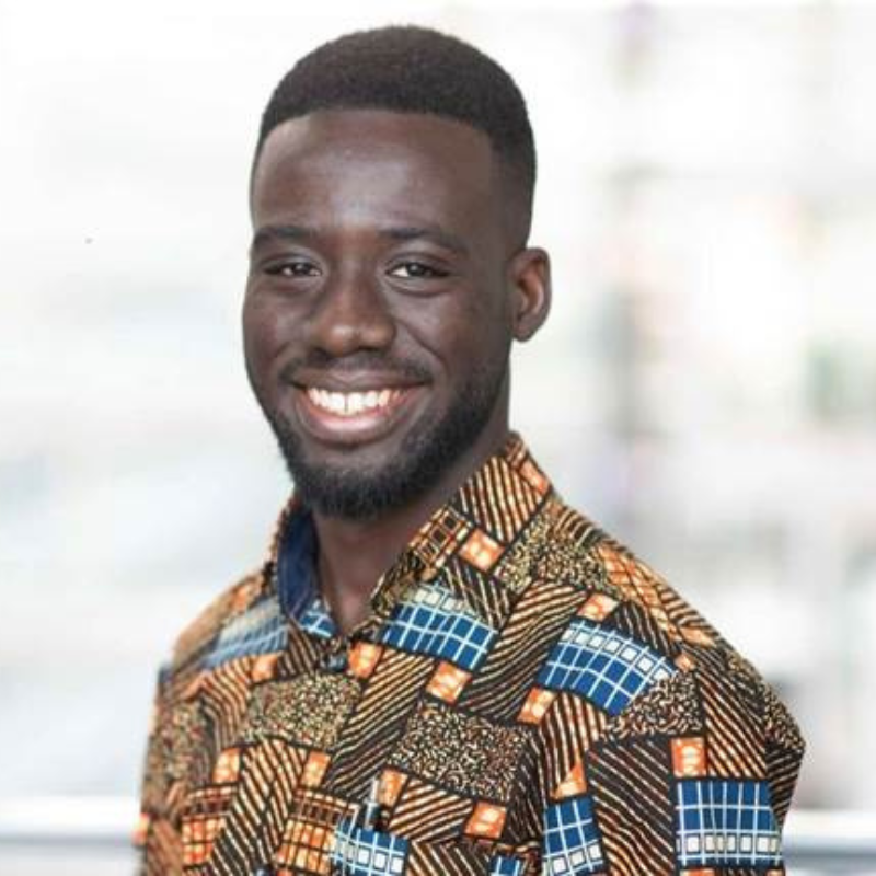 David Sasu smiles in front of a bright window.