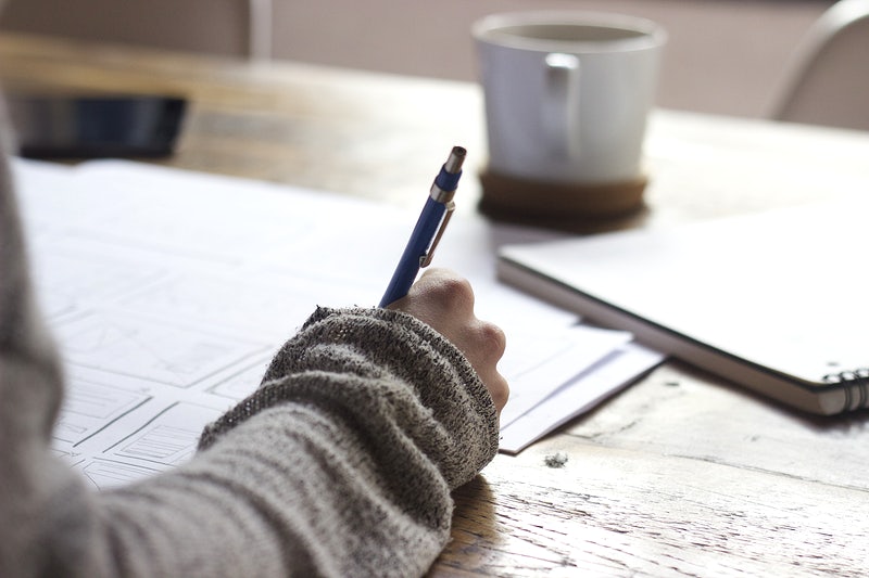 stock image of student writing at a desk.