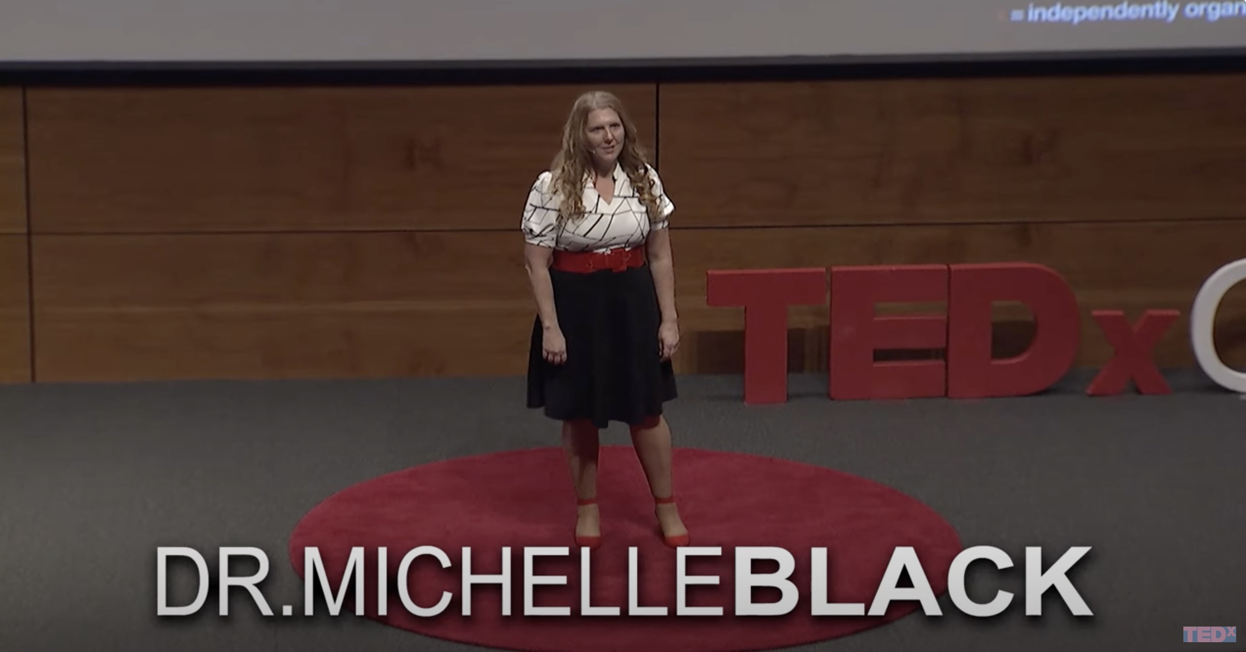 Michelle Black stands on a stage giving a presentation. 