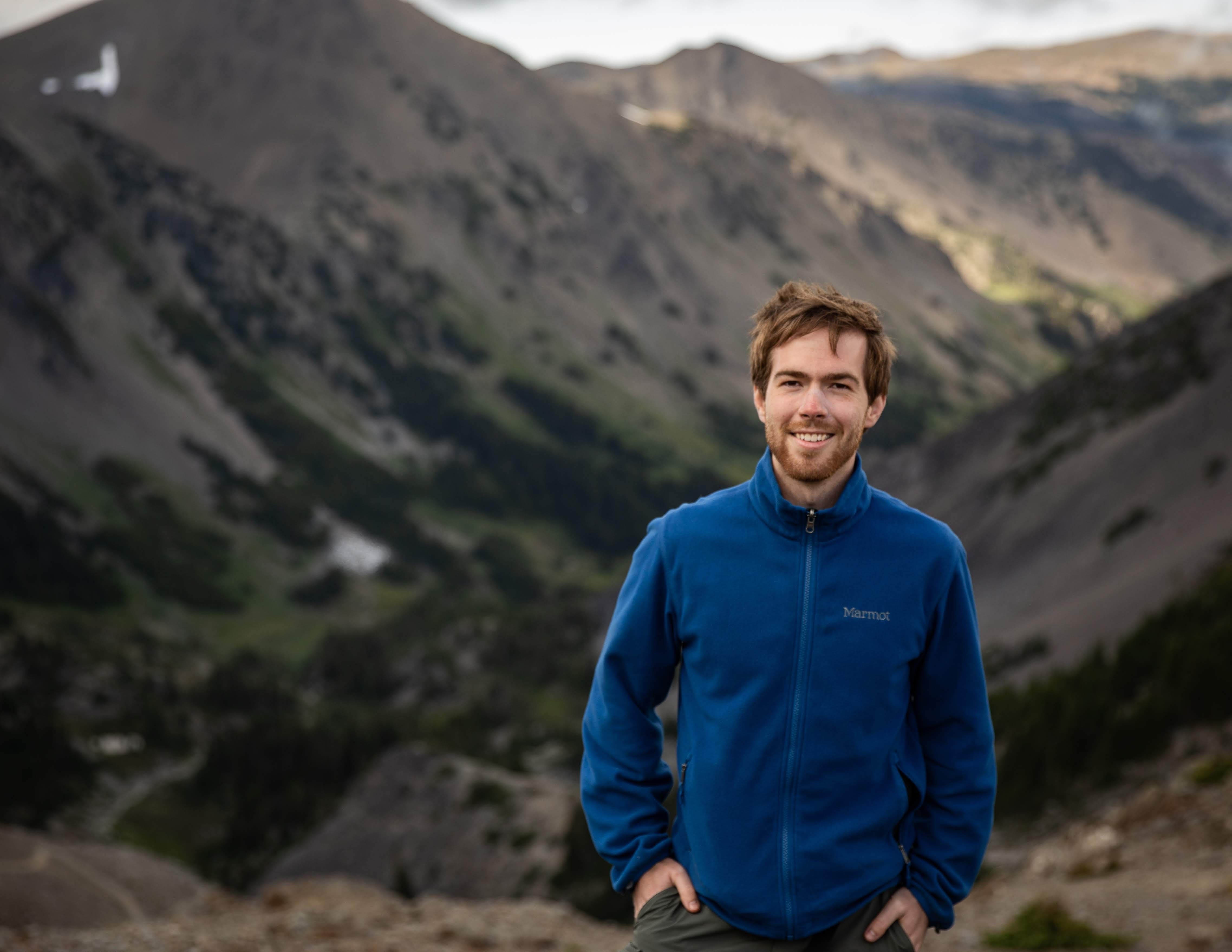 Photo of Daniel Miller in a blue jacket standing in front of a valley.