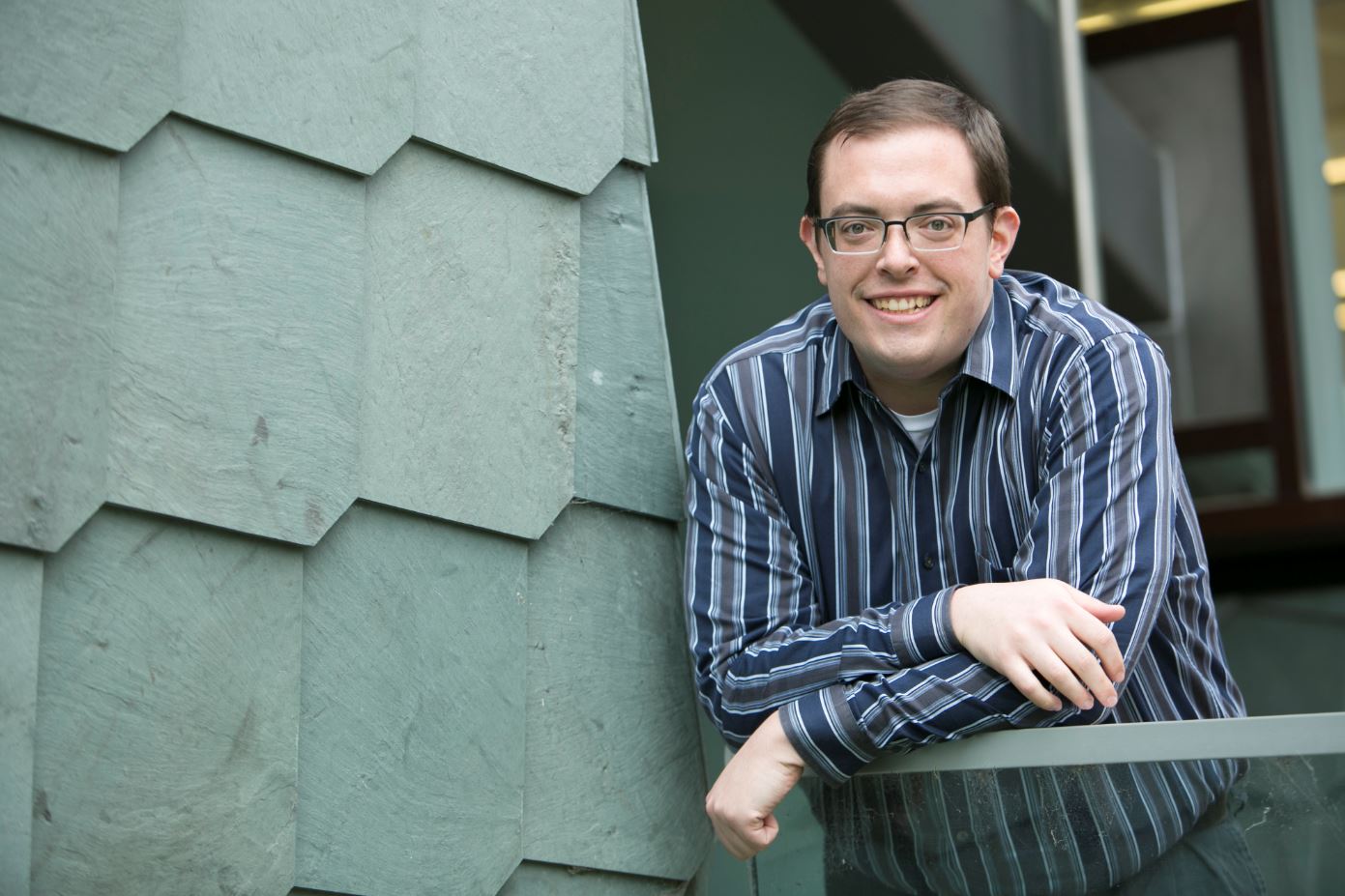 a headshot of Zachary Zaiss, smiling while leaning on a wall.