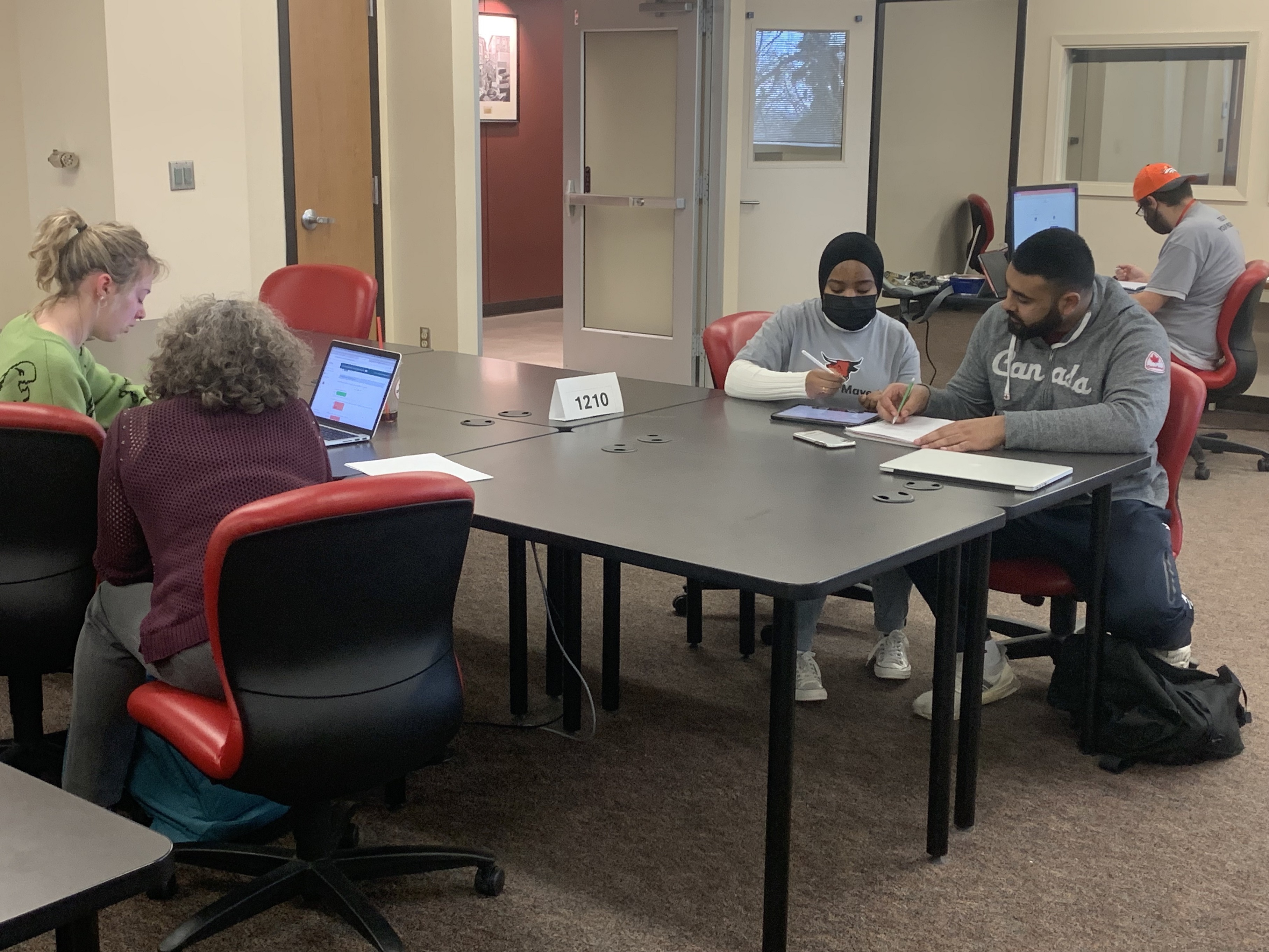 Students and Learning Assistants sit at a table and work on homework together.