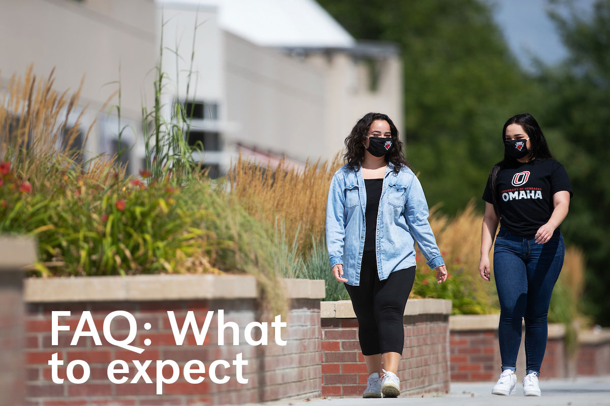 Two female students walking on campus wearing masks