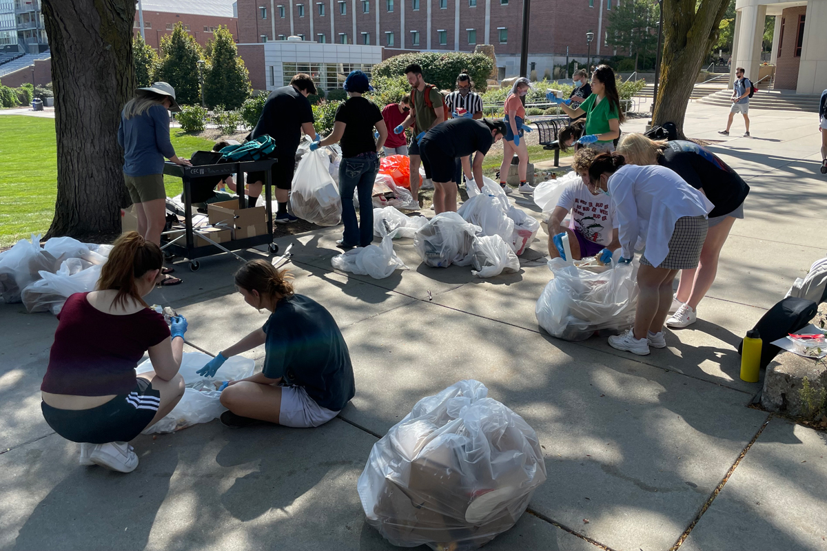 a group of students sorting through trash bags