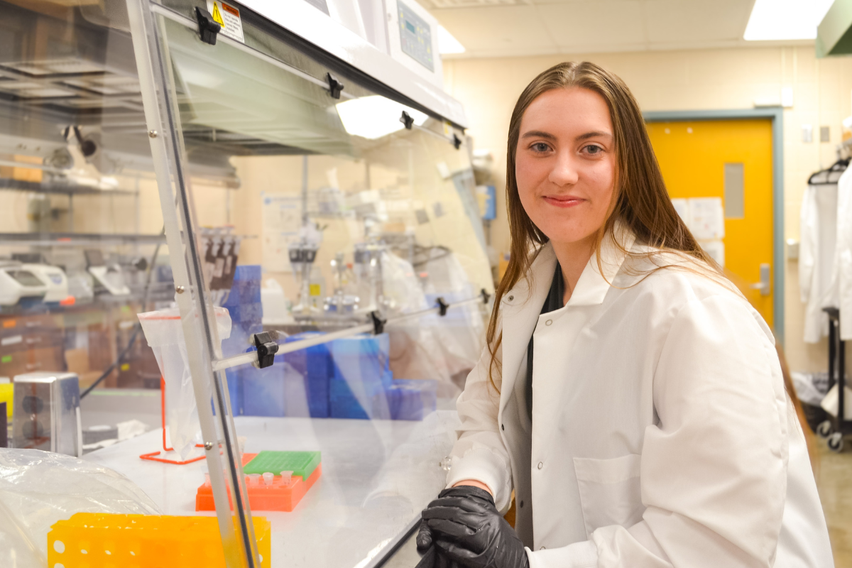 Tai Prauner sits in a research lab. She is wearing a white lab coat.