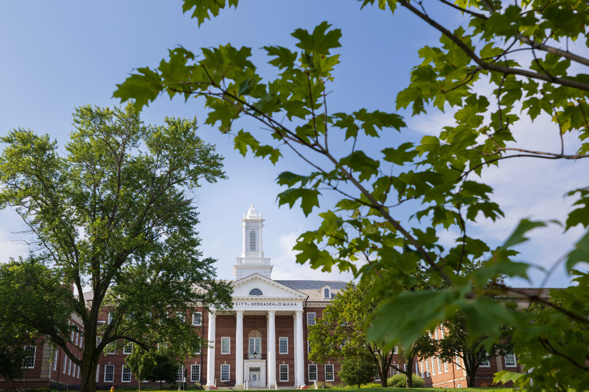 Arts & Sciences Hall is a brown brick building with a white tower in the middle of it. 