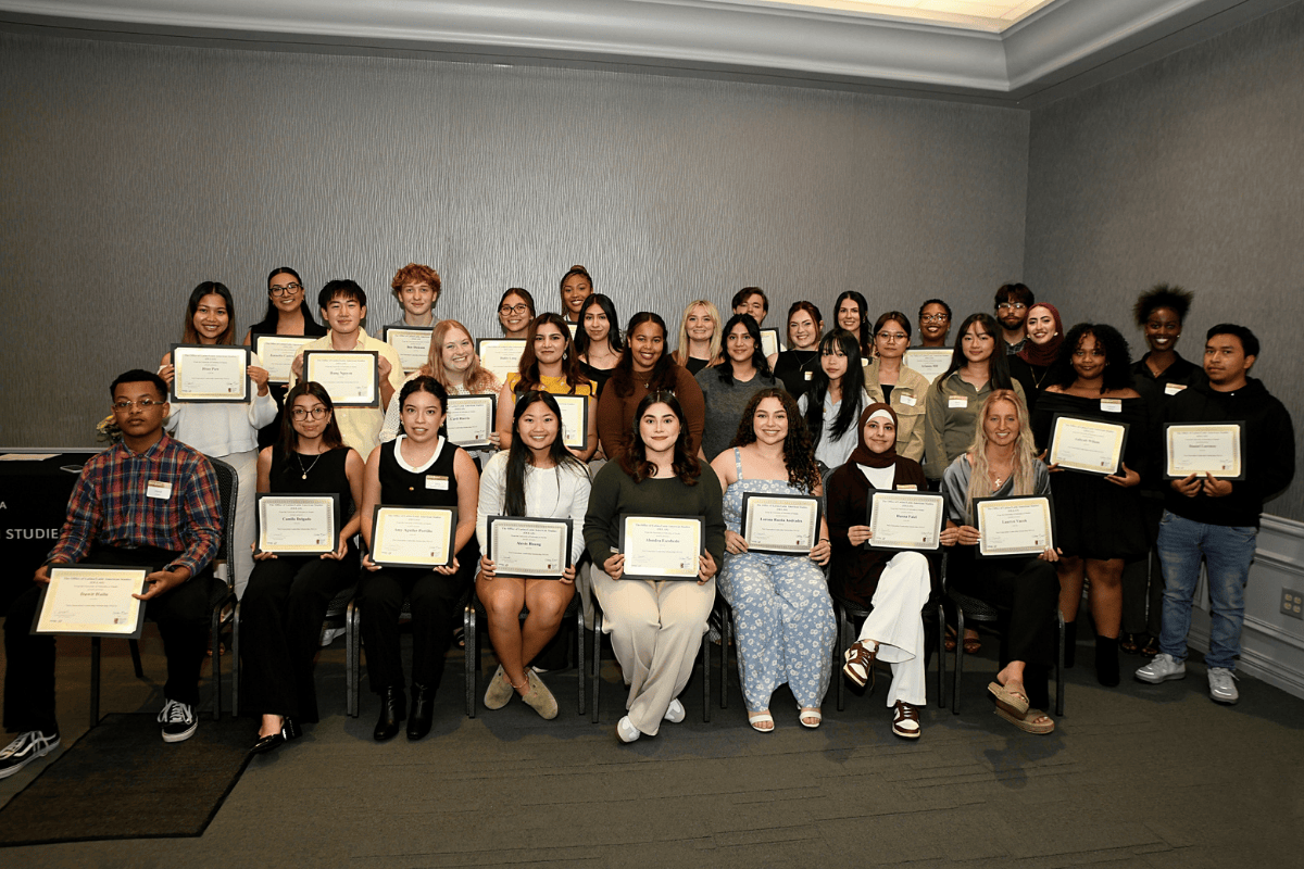 A group of students stand together smiling with their scholarship awards.