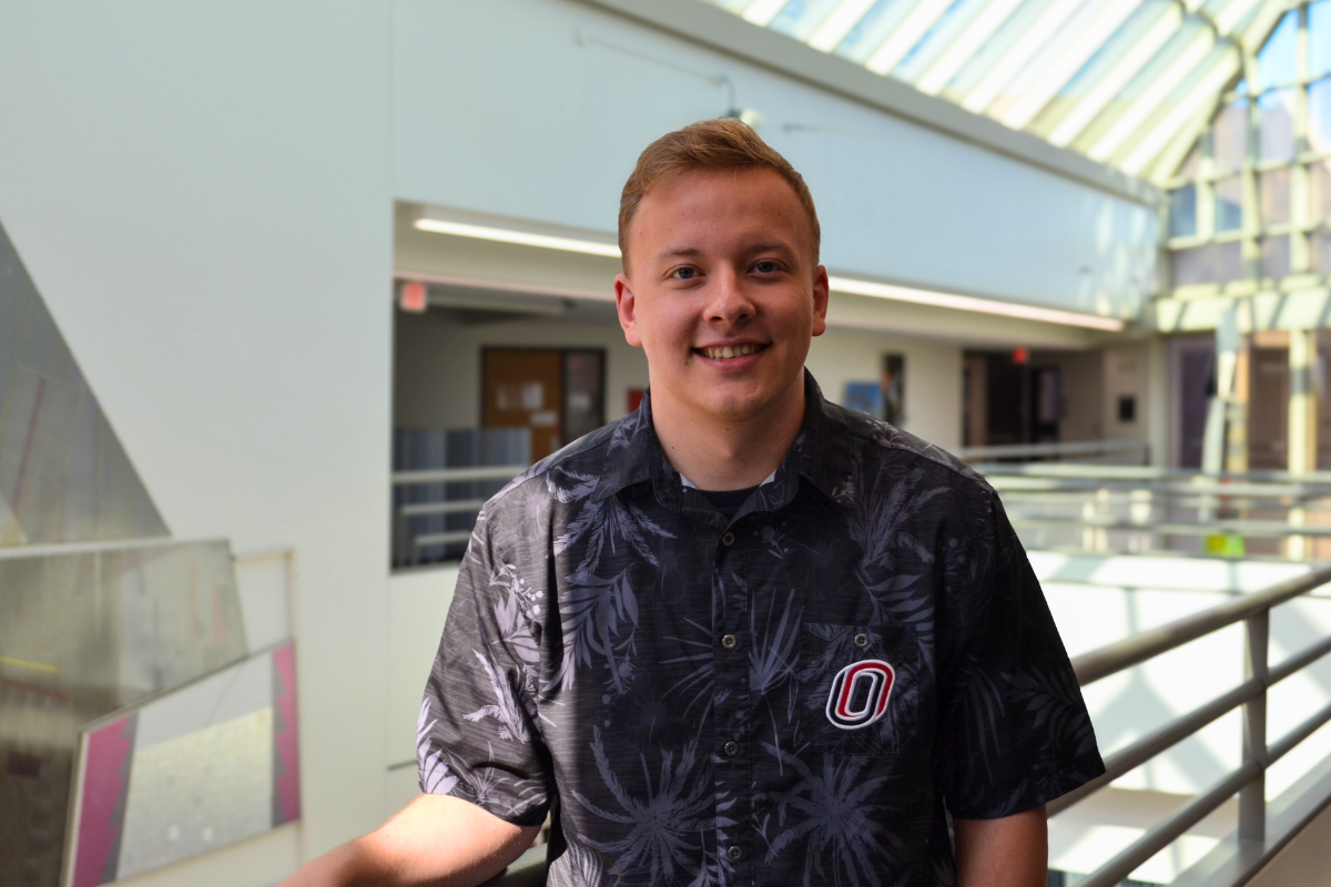 Zach Venn smiles as he stands in a bright, sunny room.