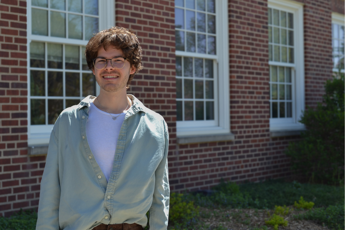 Joel Jarusek stands in front of a brick building. He is wearing a green shirt.