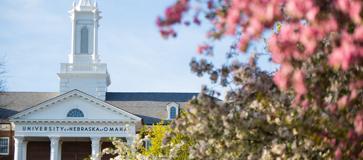 The University of Nebraska at Omaha's College of Arts and Sciences Hall surrounded by blossoming trees.