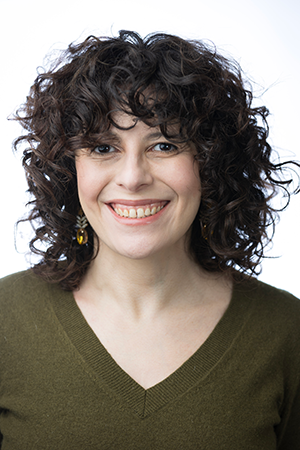 Dr. Abigail Folberg has dark curly hair and is wearing a green shirt.