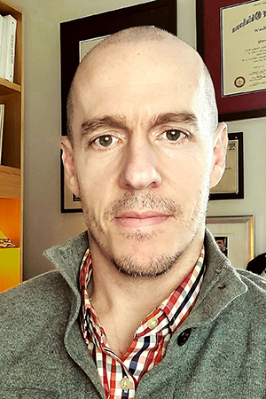 Dr. Samuel Hunter is wearing a gray jacket and white shirt.