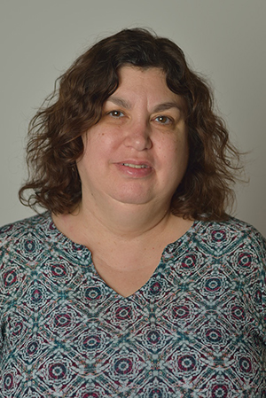 Dr. Roni Reiter-Palmon has dark wavy hair and is wearing a black and white patterned shirt.