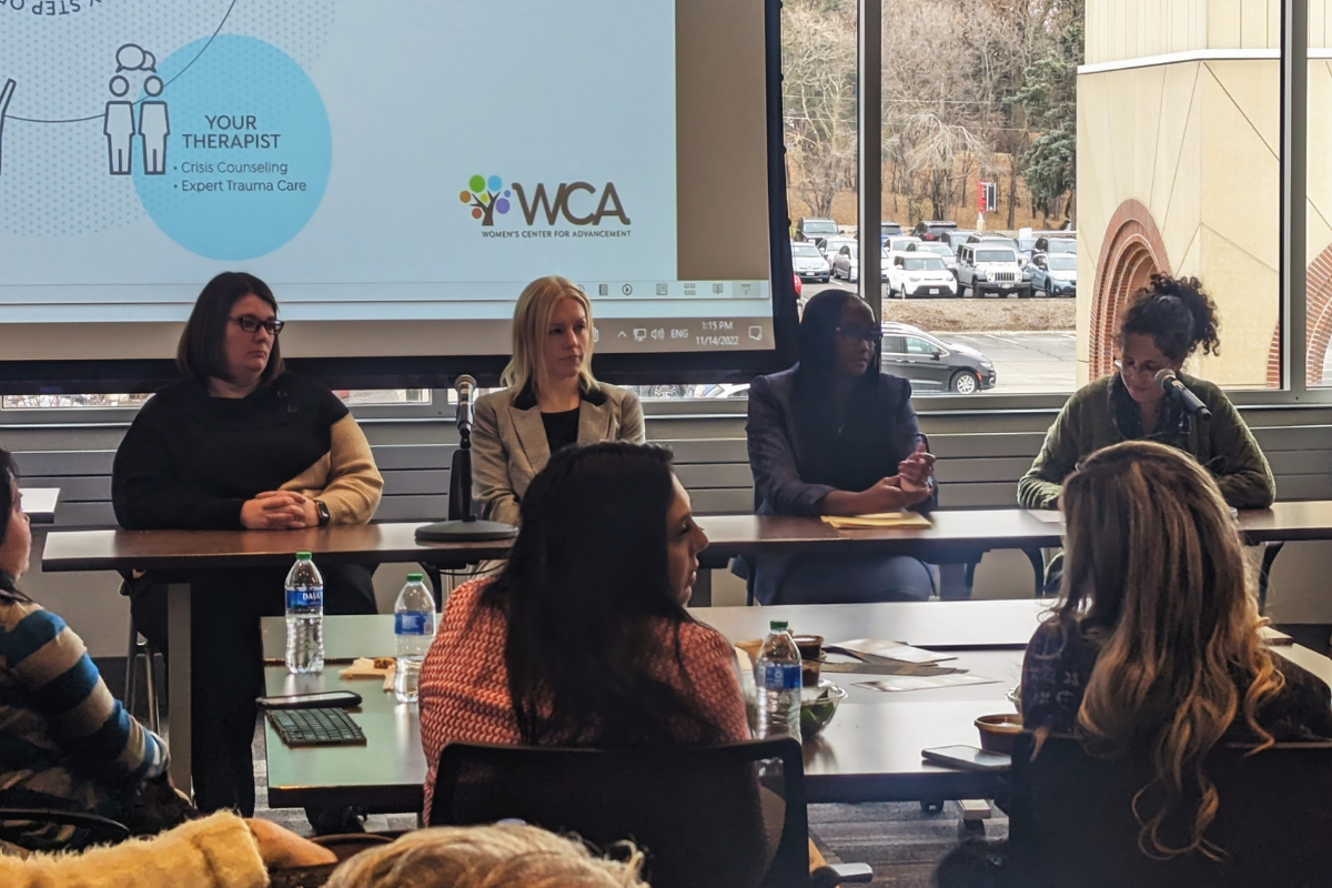 Panelists speak at a conference.
