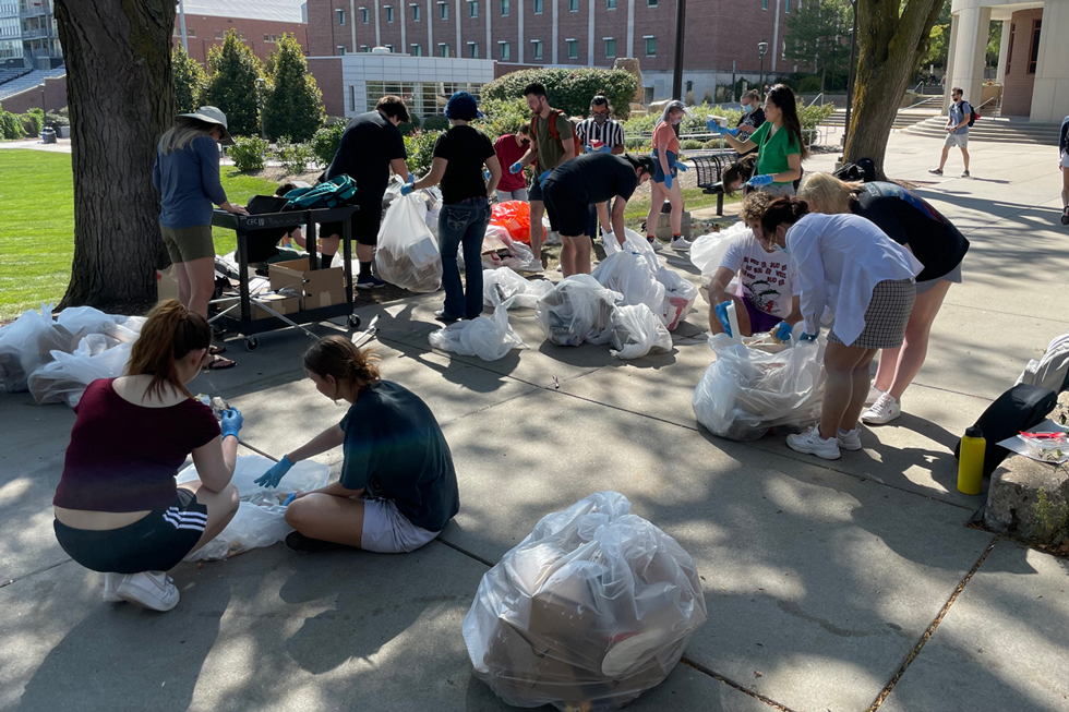 students outside sorting through trash bags