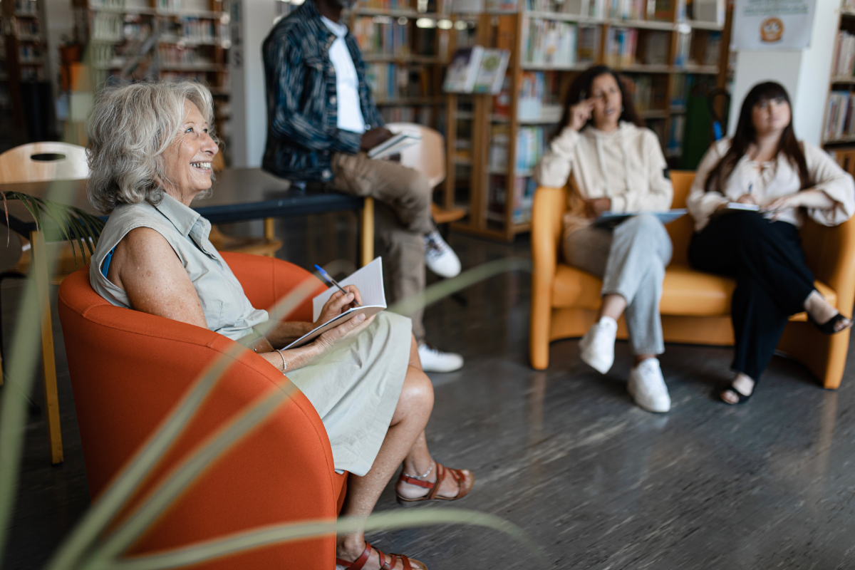 A woman sitting in an orange chair and studying with others.