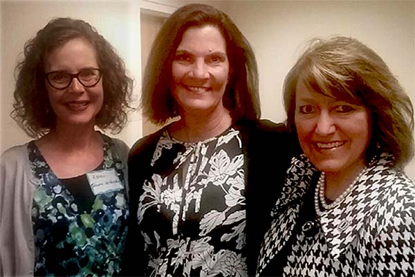 Three professors stand together and smile.