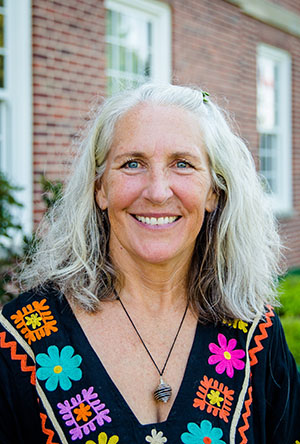 Woman with gray hair to shoulders wearing multi-colored top