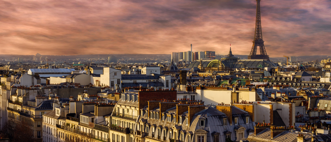 The tops of historic buildings in Paris, with a view of the Eiffel Tower. 