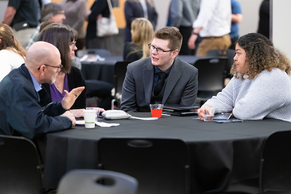 group of students seated in a round table having a conversation.