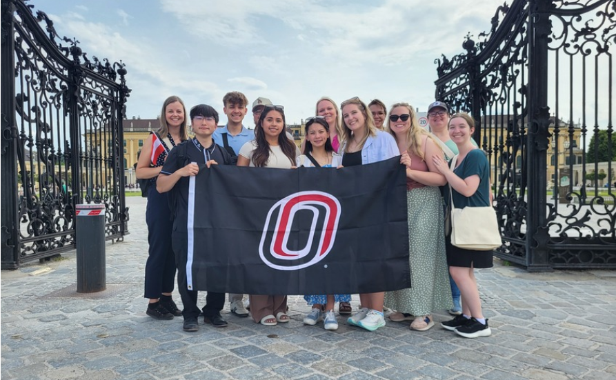 students holding up a flag with the uno logo on a study abroad trip