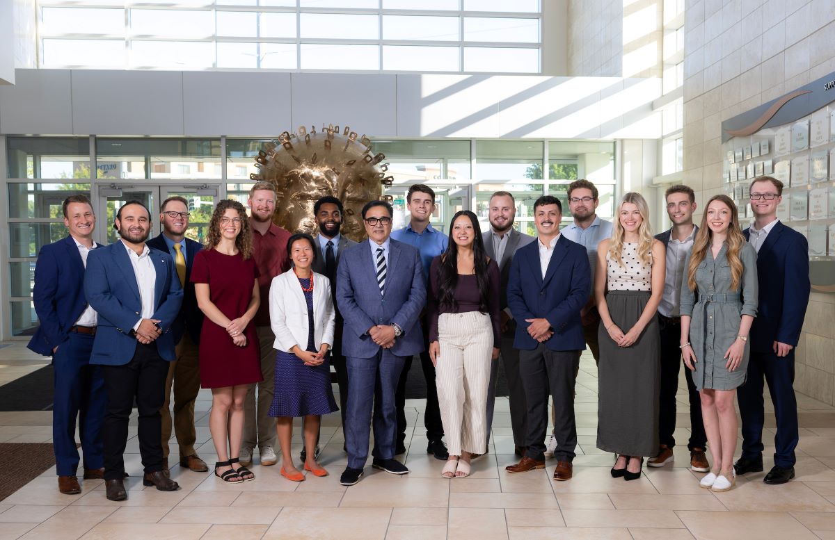 Group of College of Business Administration students, faculty, and staff posing together in the atrium of Mammel Hall.
