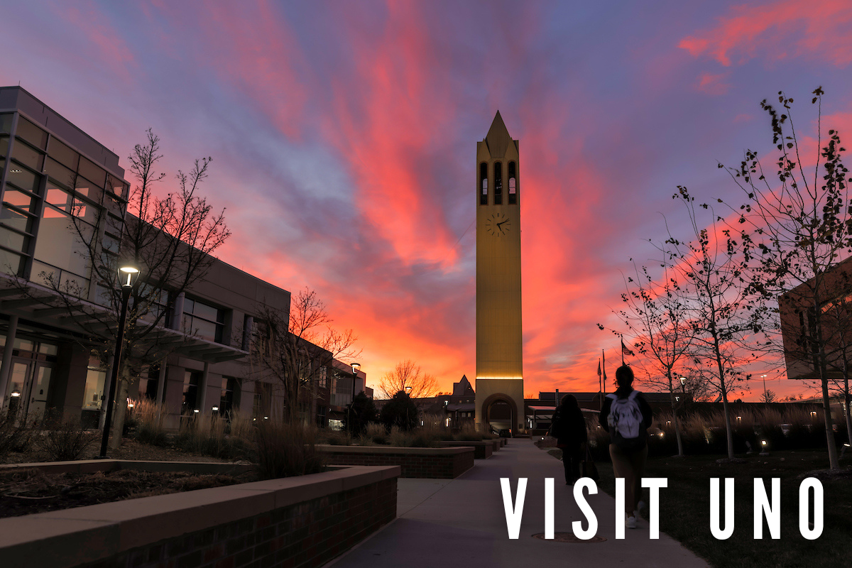 An image of a campanile and a student walking towards it. It's sunset. Text on the image reads "Visit UNO".