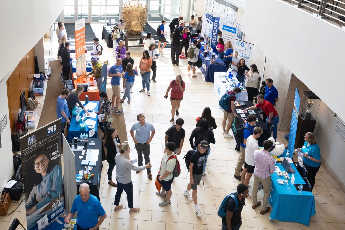 Noon at Mammel Hall Atrium, students and employers networking and conversating. Branded Booths displaying the Employer's Companies are shown in image.