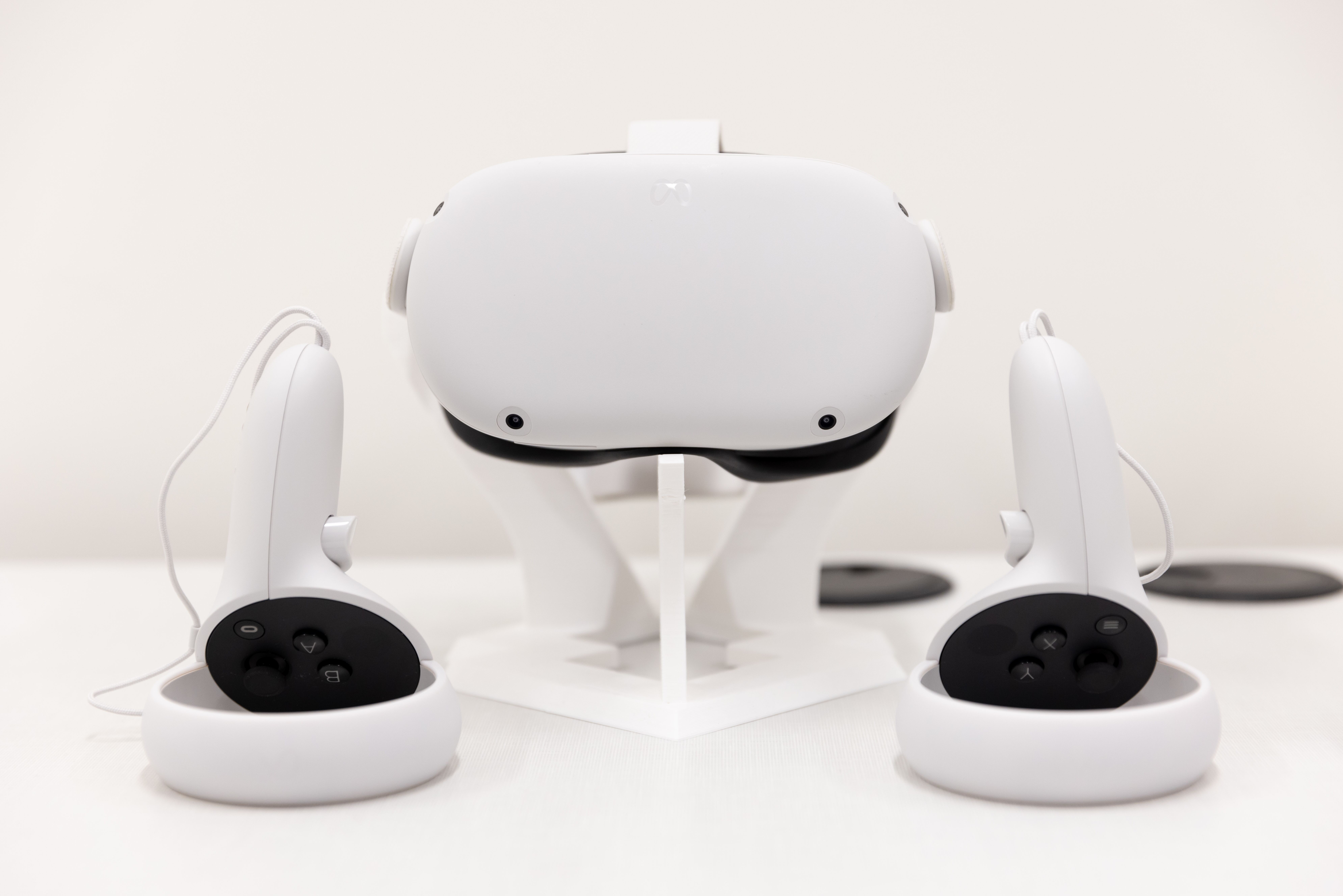 A VR headset on a stand with controllers upside down one on each side.
