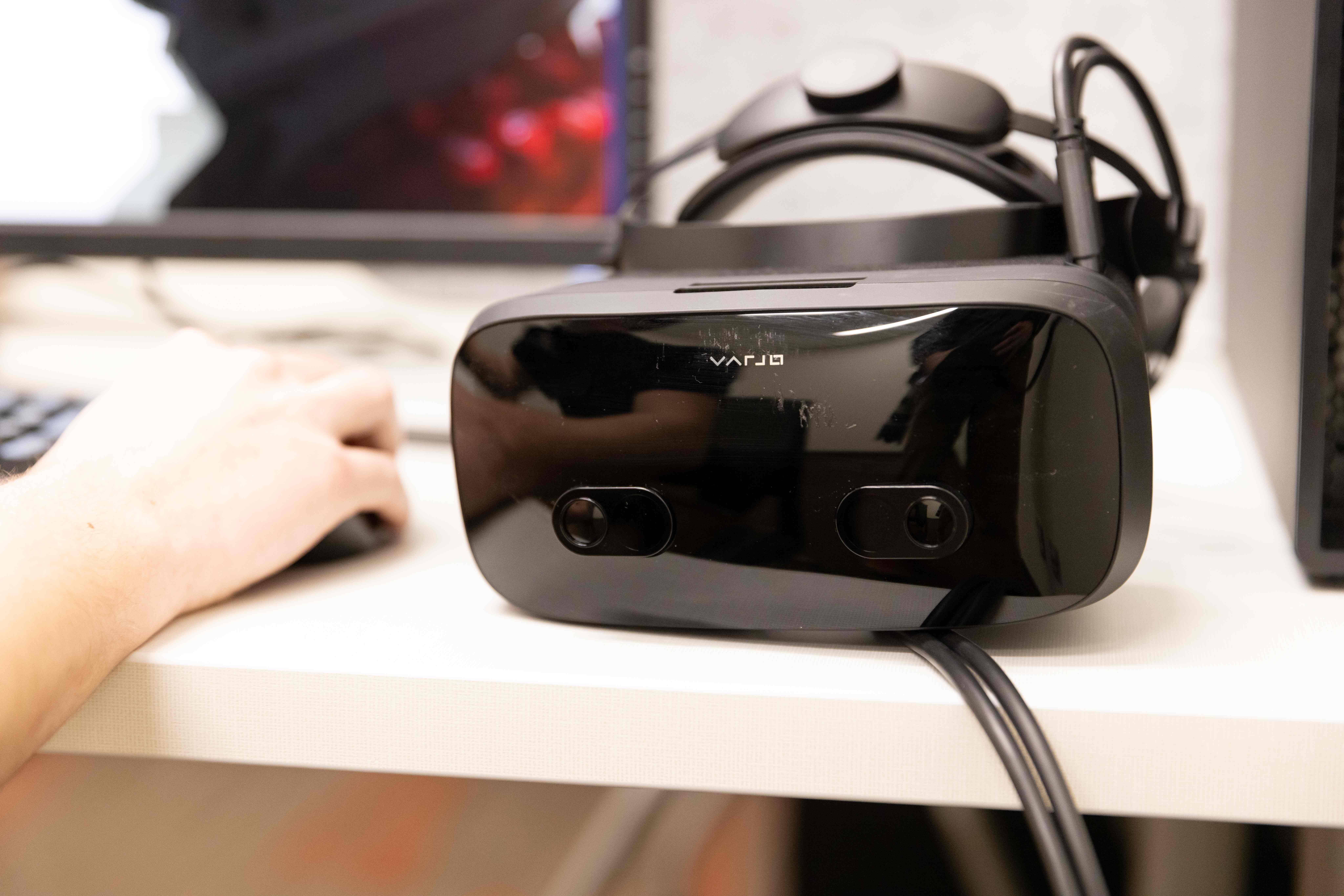 A VR headset sitting by a hand with a cord attatched to the headset