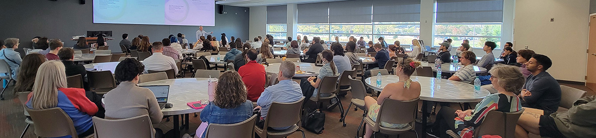 A seminar speaker talking to a large croud.