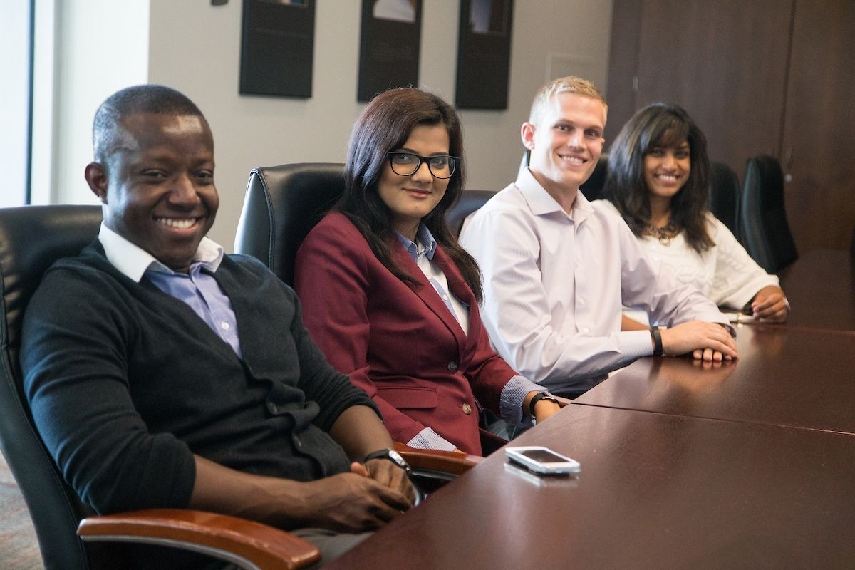 A group of students at a table smiles at the camera