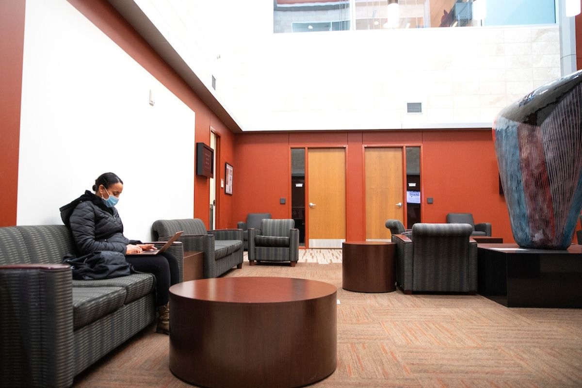 A woman works on a laptop in a college lobby