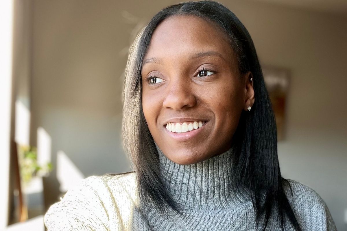 An image of a woman smiling and looking to the side of the camera