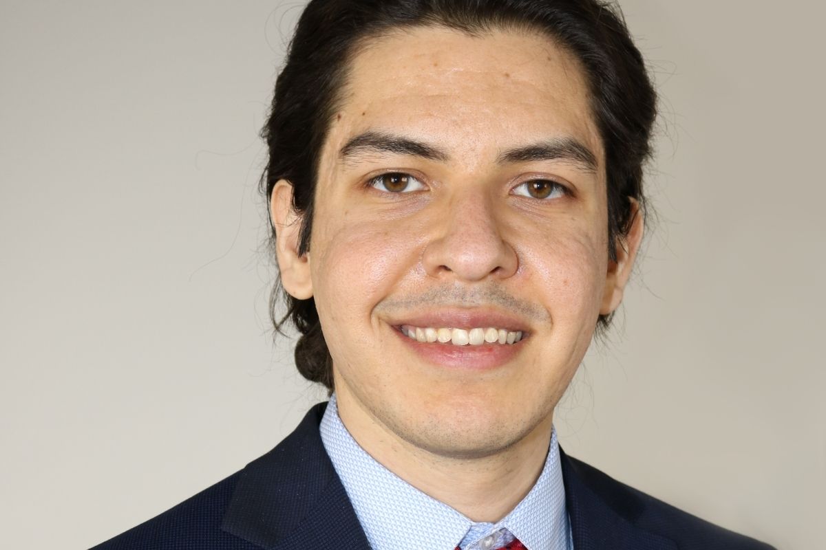 An image of a man smiling at the camera in a suit