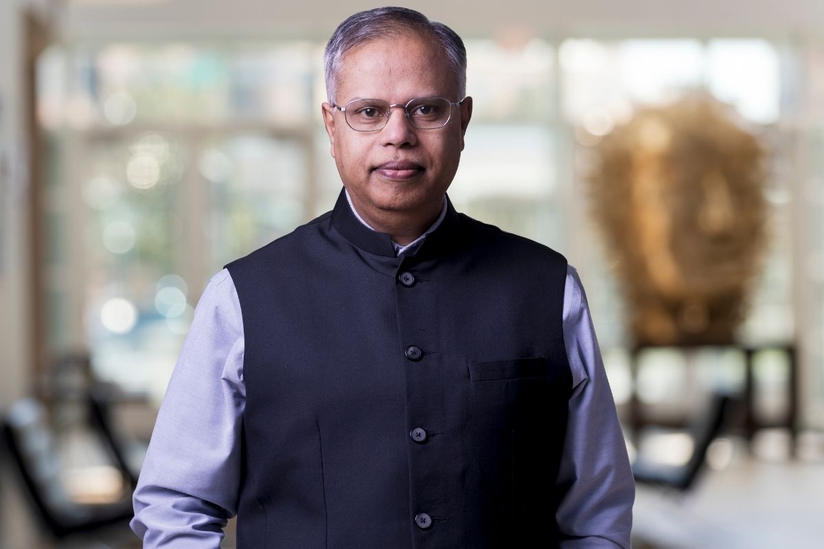 An image of a man looking at the camera in front of windows