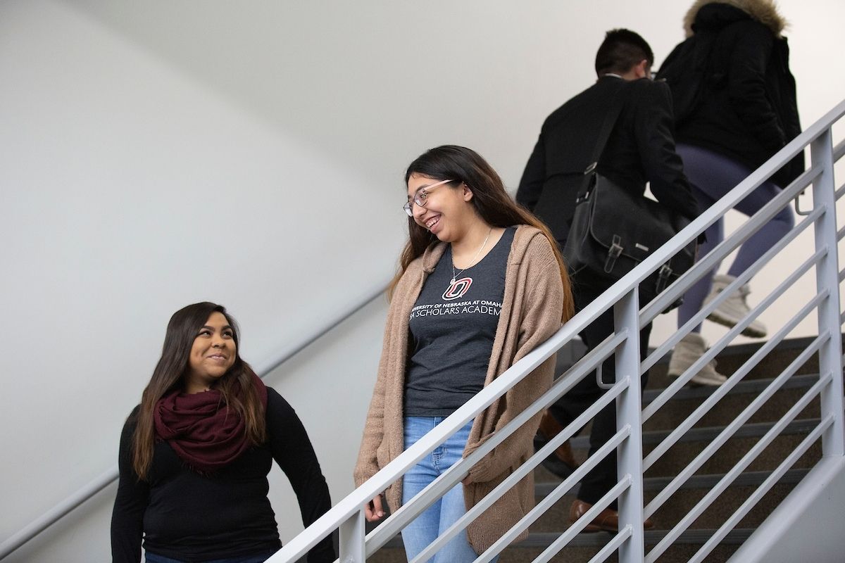 An image of two women walking down stairs and laughing together