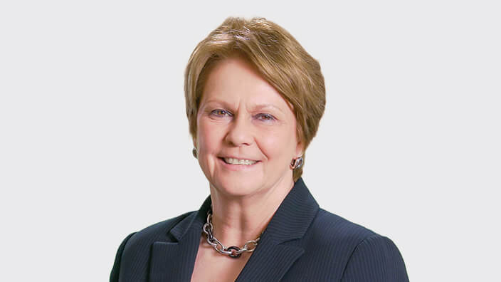 An image of a woman smiling at the camera in business clothes