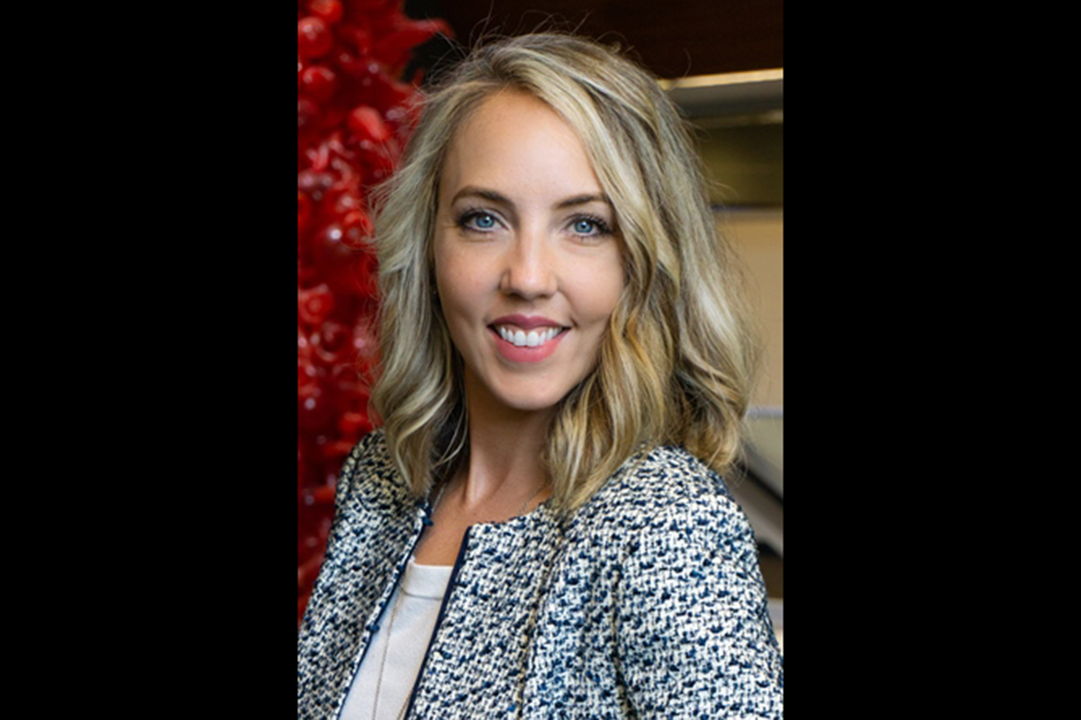 An image of a woman smiling at the camera in business clothes