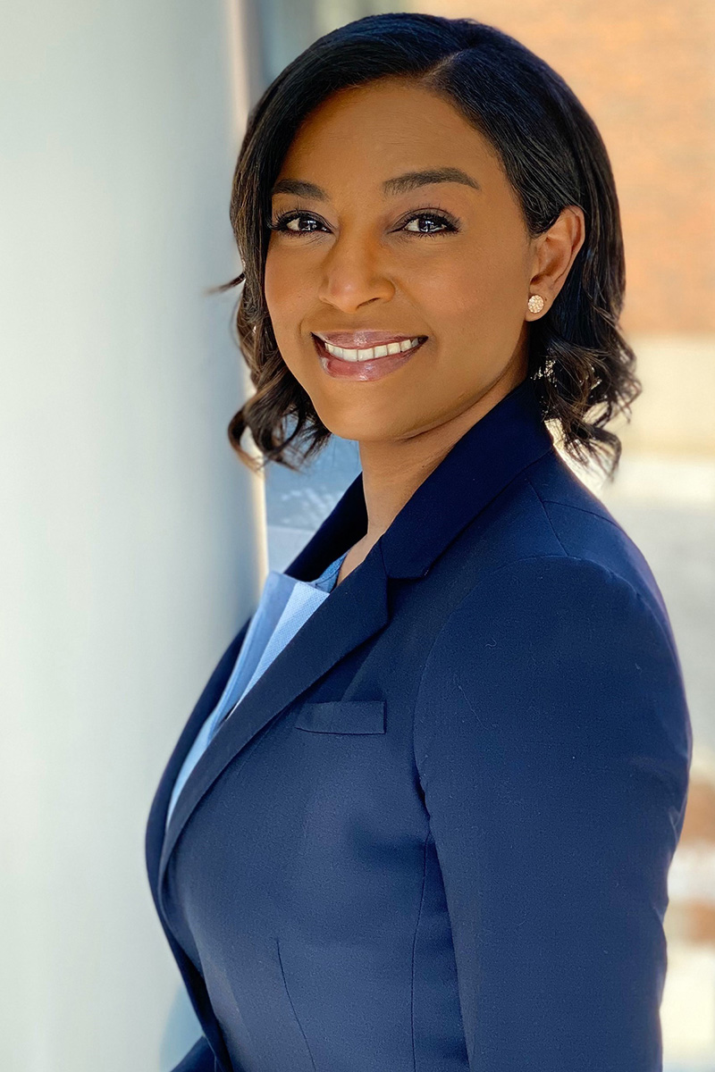 An image of a woman in business clothes, smiling at the camera