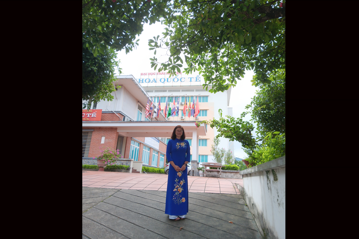 Catherine Co wearing Vietnam’s traditional dress, the ao dai. In front of a building