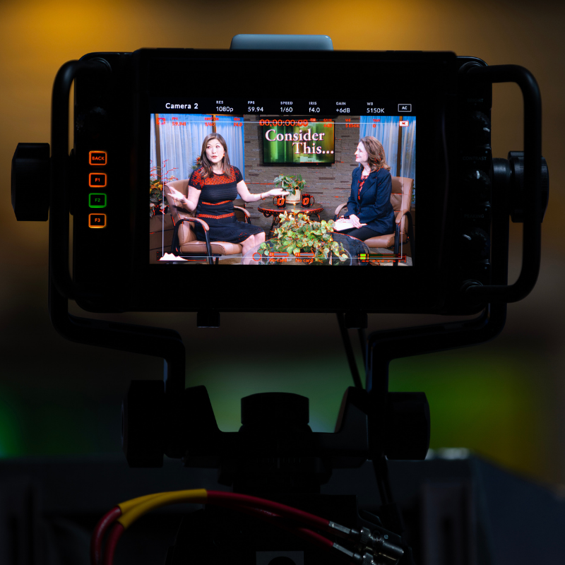 two ladies talking in front of a camera.