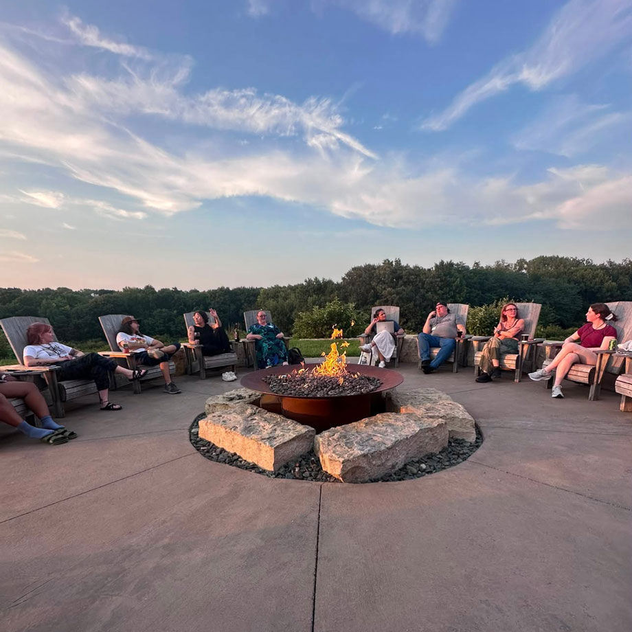 Students sit around firepit. 